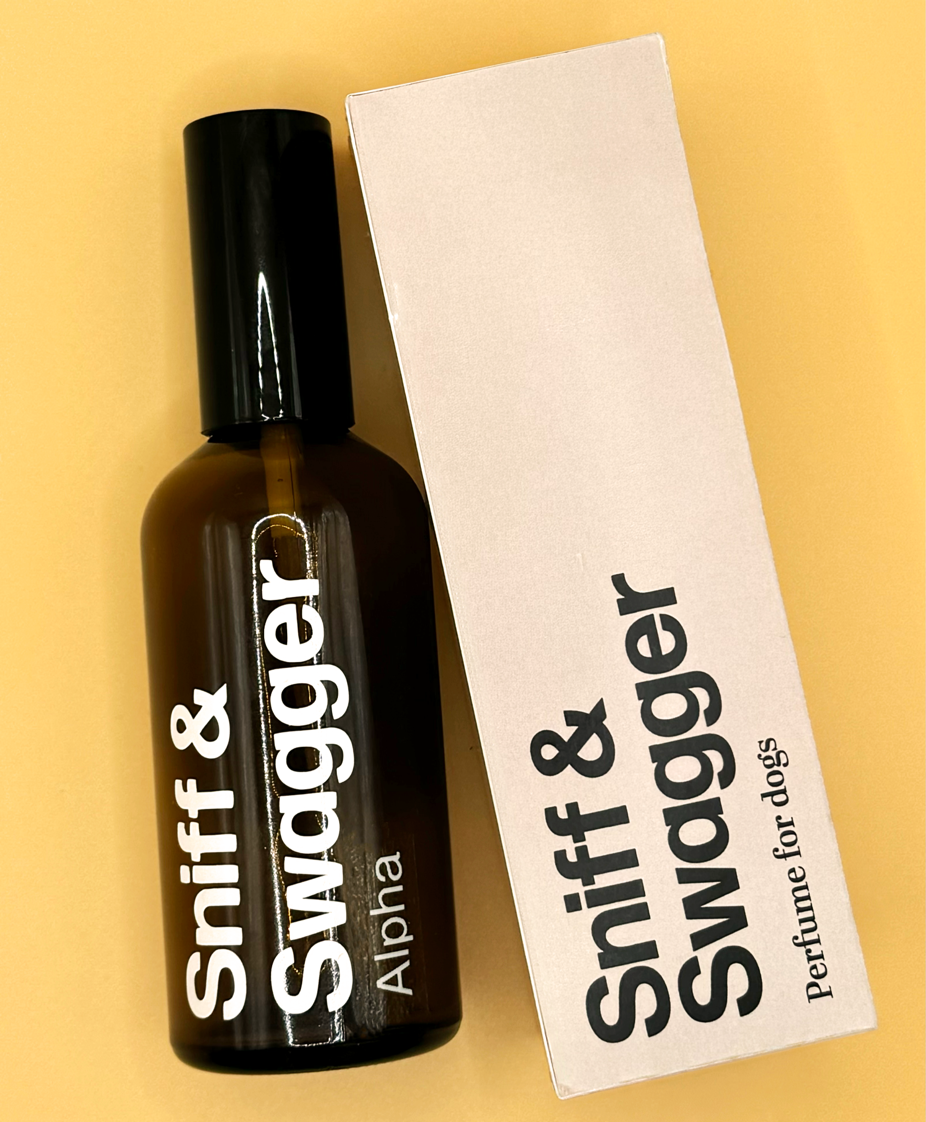Product shot of Sniff & Swagger, Alpha - perfume for dogs. Beige box and brown glass bottle on yellow background.